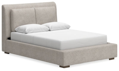 Ashley Furniture Cabalynn upholstered bed with a tufted headboard and neutral fabric, shown from an angled side view.