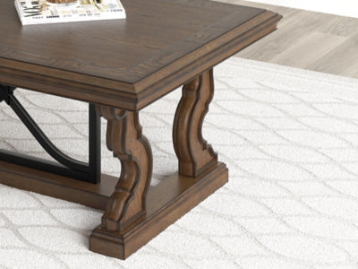 Maylee cocktail coffee table by Ashley Furniture with a sleek wooden top and modern design, shown in a detailed close-up view.