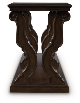Ashley Furniture Maylee sofa table with a sleek wooden surface and modern design, shown in a living room setting.